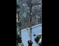 Woman in a shiny outfit poses beside the building window