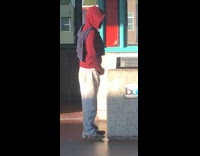 Man red jacket pees into trash can at metro train station