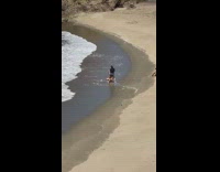 Black bikini girl kneels empty beach sand 