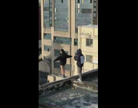 Woman in black jacket hoodie poses on the building edge