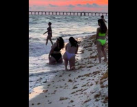 Woman in bikini kneels and over the shoulder pose