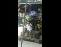 Boy dances on flower stand in front of florist while holding speakers