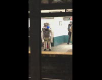 Robot costume in tinfoil waiting for train