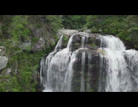 Drone flies backwards waterfall flat rocks guy