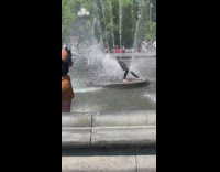 Guy stretches over water fountain in wet suit