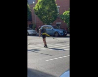 Guy wearing backpack crossing crosswalk dragging weights to train 
