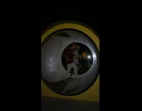 Two guys run inside a giant wheel and fall