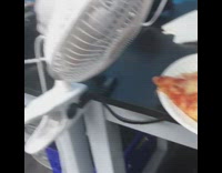 Pizza on a plate fanned by an electric fan