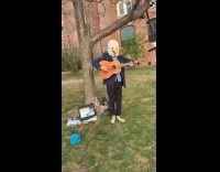 Guy wearing eagle mask plays acoustic guitar 