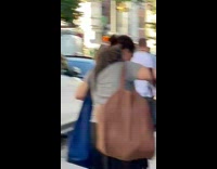 Woman walks around street with cat hanging onto shoulder