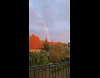 Full rainbow arch over houses trees sunset