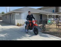 Black sweater guy sits orange motorcycle smoke 