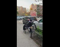 Guy sits at table with laptop on sidewalk 