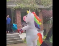 White inflatable unicorn costume dances by house 