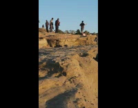 Man in black polo stretches first for a beach photoshoot
