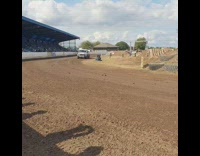 Green and white car drives around racetrack 