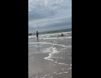 Older guy photographs lady sitting down ocean 