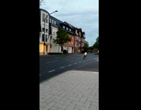 Man rides the bicycle fast on the street while friend cheers