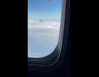 Airplane with black smoke from it seen from another plane