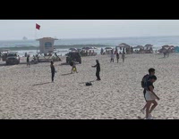 Man in tank top drinks can straight at the beach
