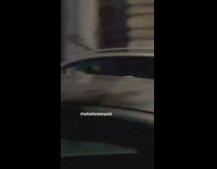 Man in convertible car singing with mic and american flag