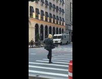 Man Dressed as Donald Trump Motions Toward Pedestrians 