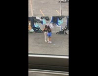 Two girls walk by grey blue mural 