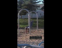 Girl hanging on playground swing facing downwards