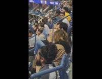 Guy at baseball game eating from a jar of peanut butter 

