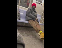 Red beanie guy smokes cigarette inside subway 