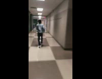Boy runs down school hallway past green lockers and jumps inside trash can, cannonball