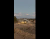 Blue car drives over dirt ramp