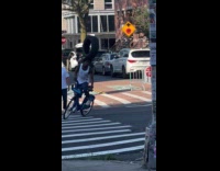Collab WINY - Man on citibike balancing tire on head 