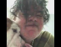 White short beard green shirt long hair man lets bulldog lick his face