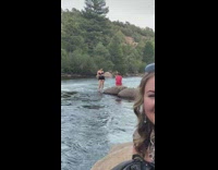 Woman in black outfit poses in the middle of the river stream