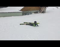 Girl green black jacket skis off ramp and falls down in snow 