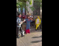 People in costumes play instruments on house steps