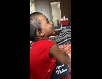 Small toddler boy sitting on bed smiling and laughing 
