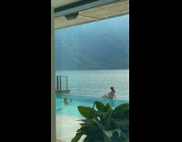 Woman in red bikini sits on the poolside with the ocean nearby