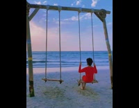 Guy on wooden swing on beach sand