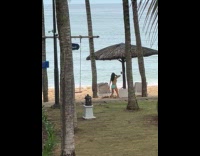 Woman holds drink shakes body at beach