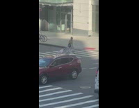 Woman carries little girl on suitcase in street