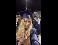 Girl at graduation ceremony points middle finger 