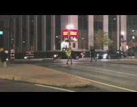 Man in yellow vest no pants blows whistle and directs traffic on street