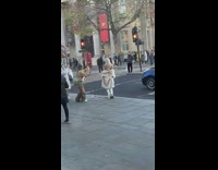 Woman with white coat and boots poses on the sidewalk