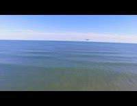 Drone flies over ocean water beach houses 