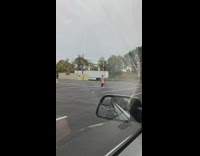 Woman in pink doing stretches in middle of parking lot 