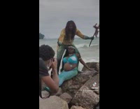 Couple doing maternity shoot at beach and husband falls off rock