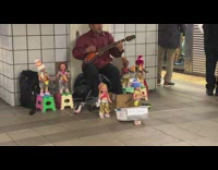 Man sing and plays guitar with dolls that dances at the subway