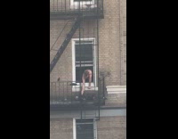 Man shirtless feeds pigeon on fire exit